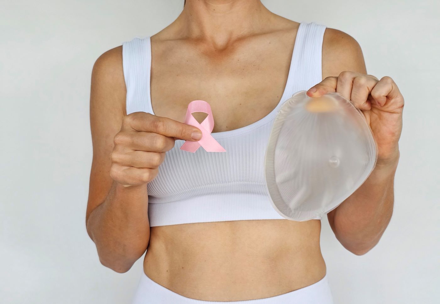 Mulher segurando símbolo do câncer de mama e silicone para representar a cirurgia de reconstrução mamária após mastectomia.