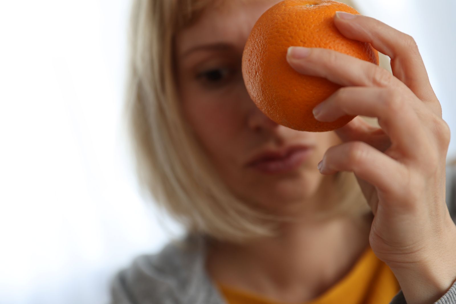 Mulher segurando laranja para representar mama casca de laranja.