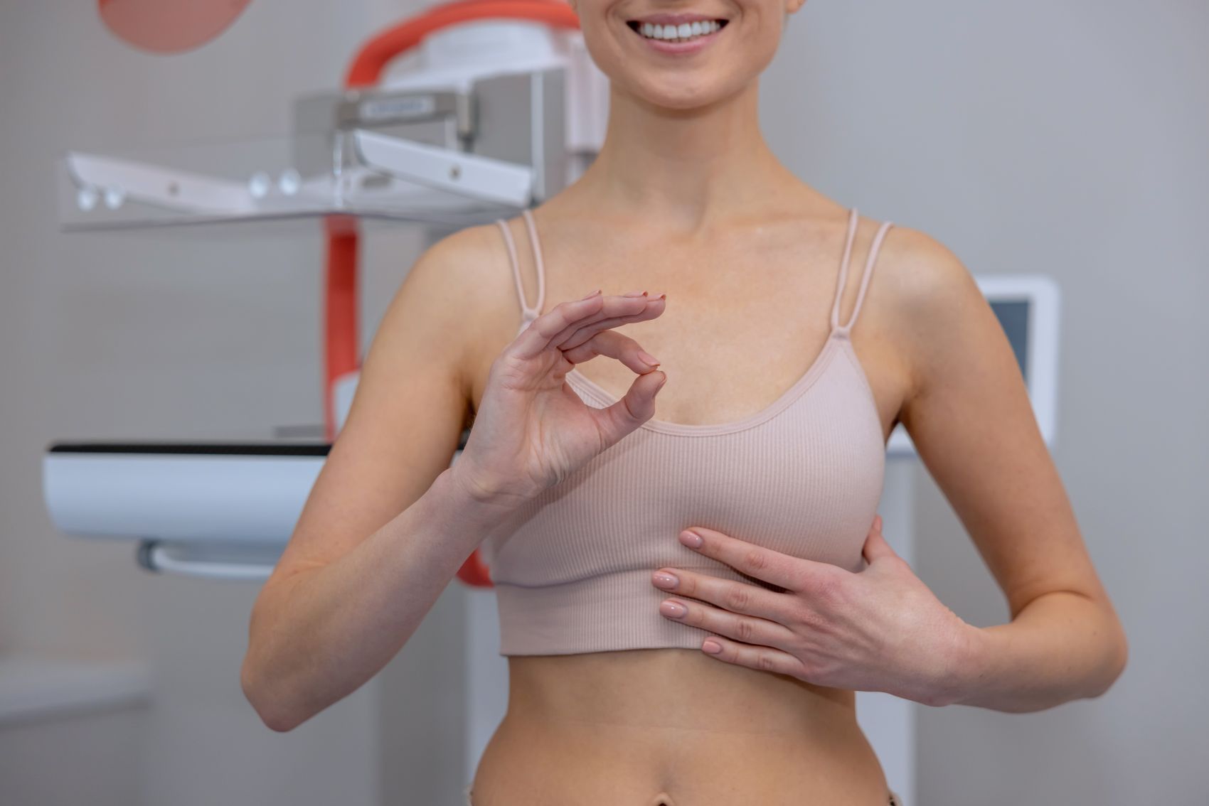 Mulher prestes a realizar exame de mamografia após saber o que causa câncer de mama realizando sinal de que está fazendo acompanhamento médico.