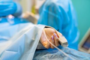 Paciente em maca hospitalar monitorada durante cirurgia, representando procedimento de linfadenectomia em tratamento oncológico.