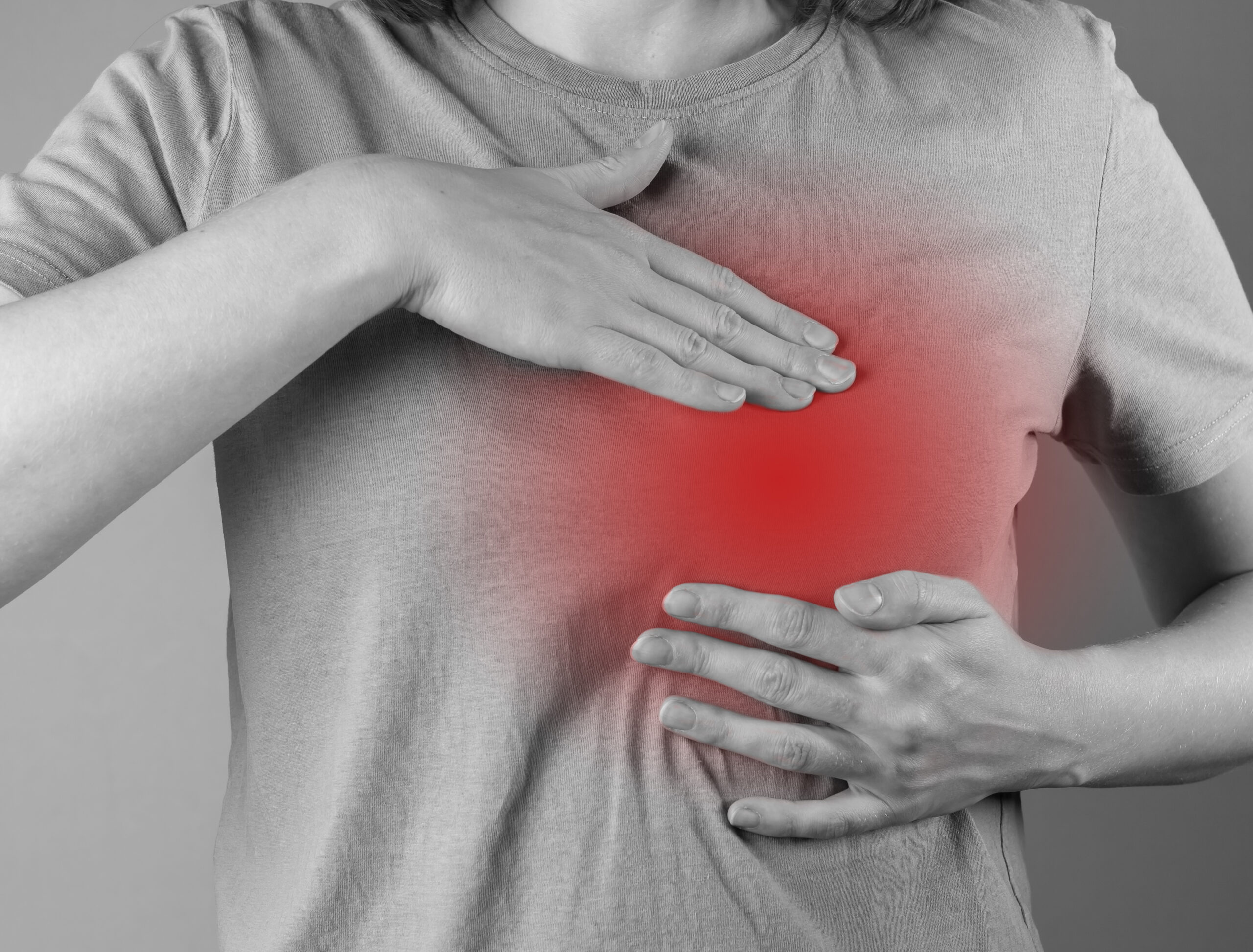 A imagem mostra uma mulher apalpando as mamas, com destaque em vermelho na área mamária representando inflamação, calor e o sintoma que gera a dúvida "vermelhidão na mama é câncer".